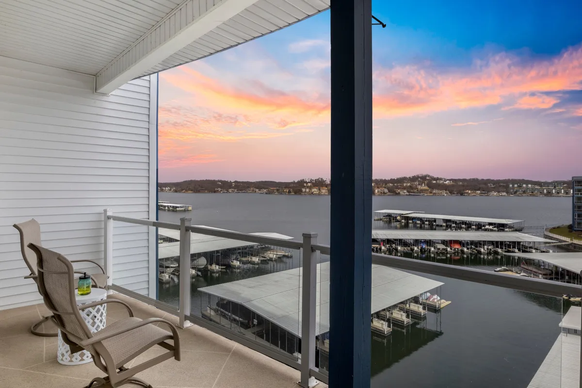 A tranquil balcony furnished for relaxation, overlooking the lake at sunset. The outdoor furniture invites guests to unwind, socialize, or simply enjoy the sweeping water views after a day of exploration.