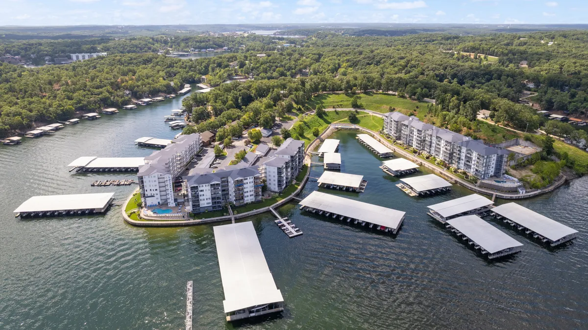 This image showcases a waterfront apartment community with a marina set against lush greenery. The view highlights both the proximity to the water and the availability of boat slips, while suggesting easy access to outdoor adventures like boating, fishing, and lakeside relaxation.