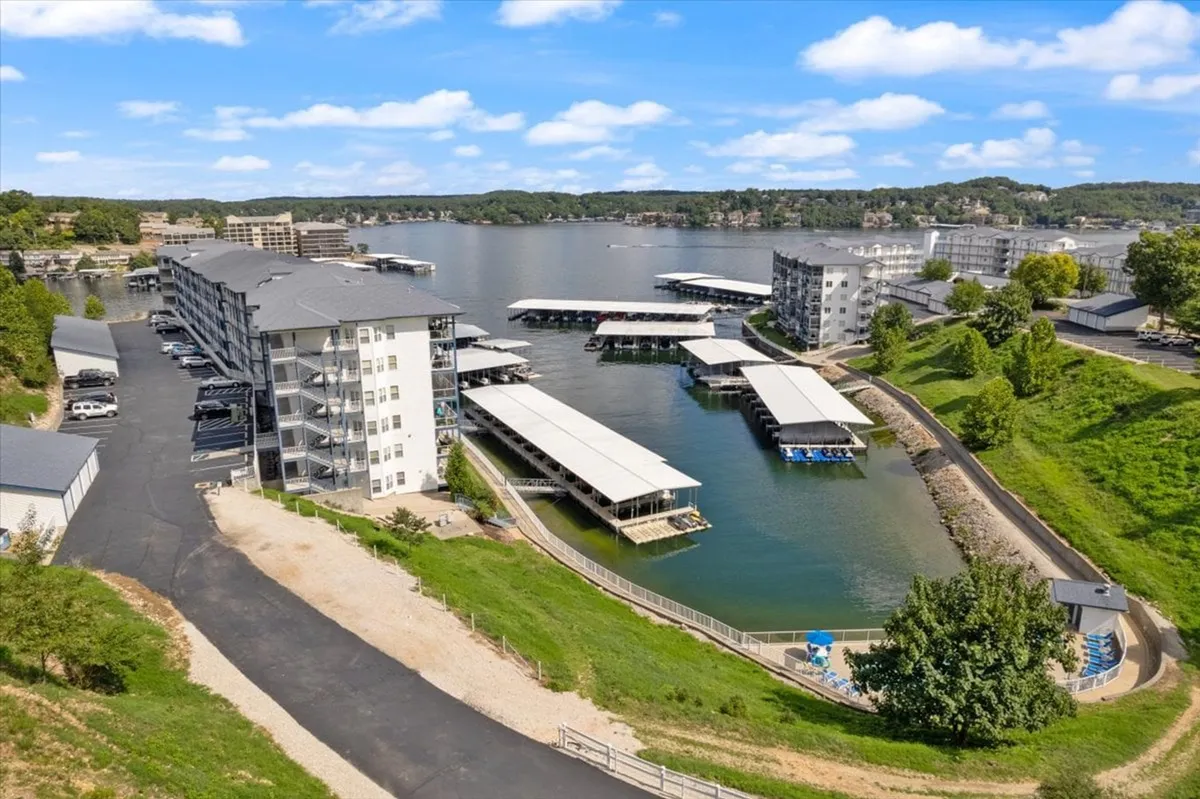 A panoramic waterfront view featuring marinas, docks, and lush greenery. The expansive waterway is the focal point, lined with boats and surrounded by natural beauty, ideal for exploration and fishing. Residential buildings and walking paths frame the scene, hinting at a lively yet serene lakeside community.